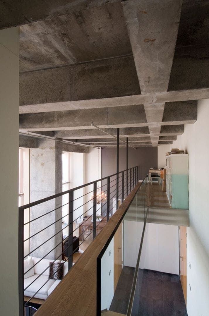 Levent Loft: açıkta bırakılmış beton kiriş ızgarası altında asma kat galerisi ve çift yükseklikli salon